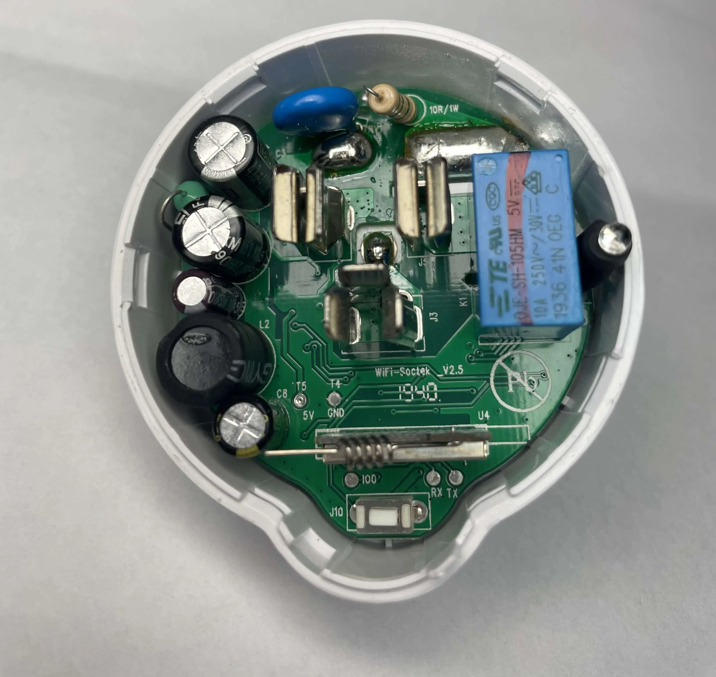 A top-down view of the Etekcity Voltson ESW01-USA-R6P's PCB. At the bottom of the PCB, there is an AI-Thinker ESP 01E module identifiable by its spring antenna. Below the ESP module, there are three test pads labeled, from left to right, as IO0, RX, and TX. Above and to the left of the ESP module, there are two test pads labeled, from left to right, as T5/5V and T4/GND.